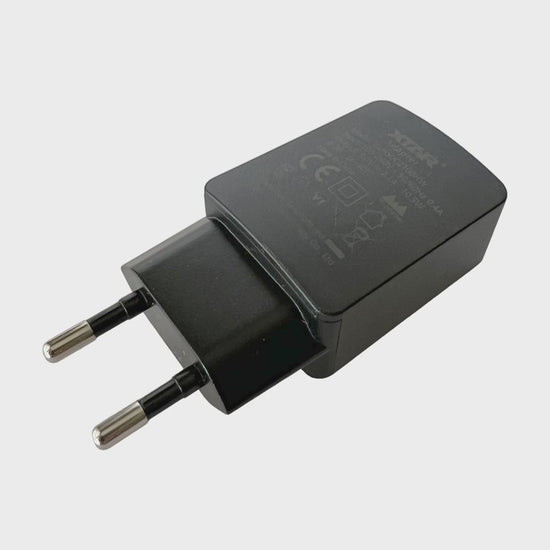 XTAR EU USB power adapter on a white background, showing the adapter, USB-A output port and original retail box.